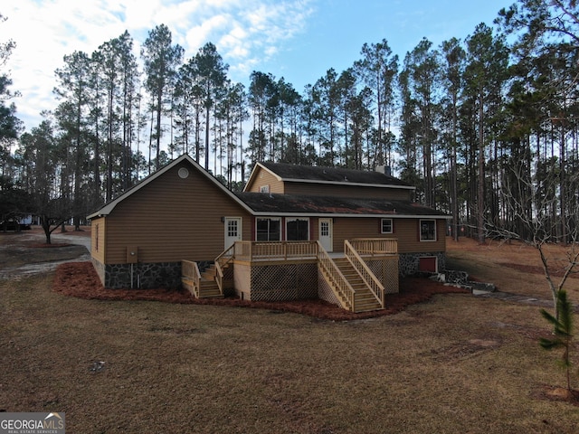 rear view of house with a lawn and a wooden deck