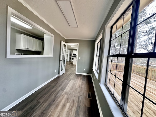 corridor featuring a textured ceiling, french doors, ornamental molding, and wood-type flooring