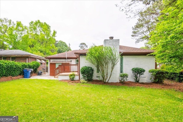 back of house featuring a deck and a lawn