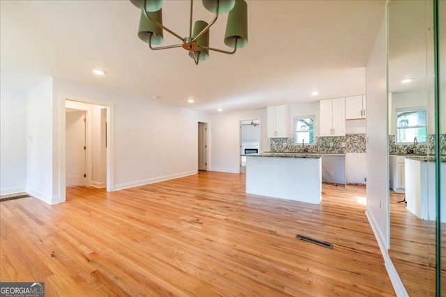 unfurnished living room with sink and light hardwood / wood-style floors