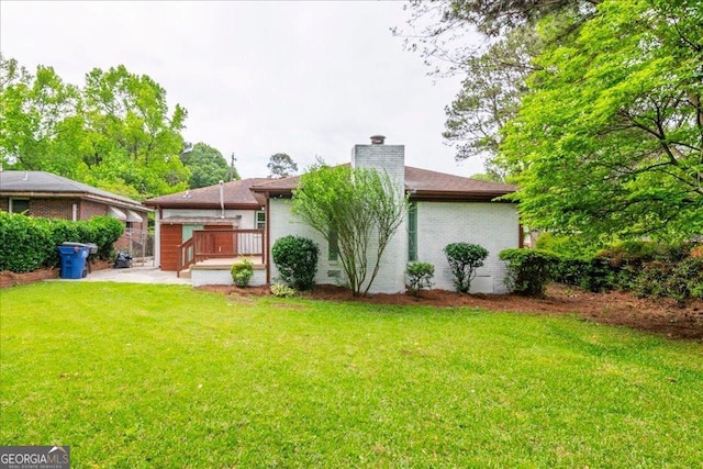 rear view of house with a wooden deck and a lawn