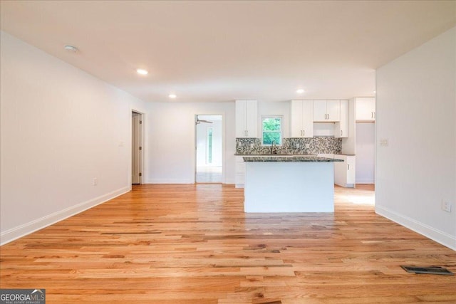 interior space featuring decorative backsplash, white cabinets, and light wood-type flooring