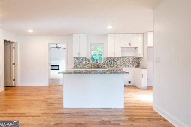 kitchen featuring white cabinetry, tasteful backsplash, dark stone counters, and light hardwood / wood-style flooring