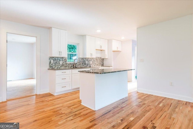 kitchen featuring sink, white cabinets, light wood-type flooring, and decorative backsplash