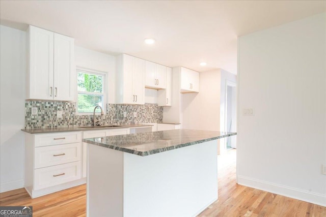 kitchen with white cabinetry, sink, tasteful backsplash, and a kitchen island