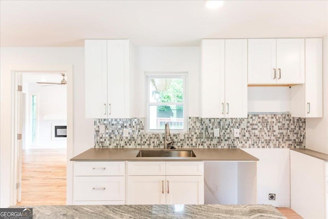 kitchen with white cabinetry, sink, backsplash, and light wood-type flooring