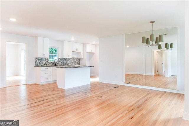 kitchen featuring white cabinetry, decorative light fixtures, an inviting chandelier, and light hardwood / wood-style flooring