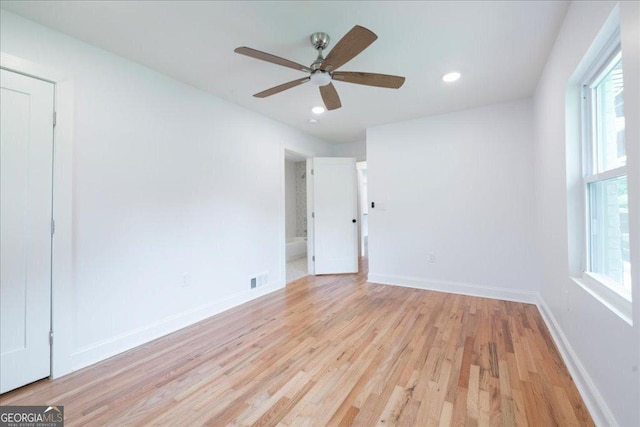 empty room featuring ceiling fan, a healthy amount of sunlight, and light wood-type flooring