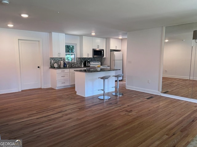 kitchen with white cabinetry, a kitchen breakfast bar, a center island, and white fridge