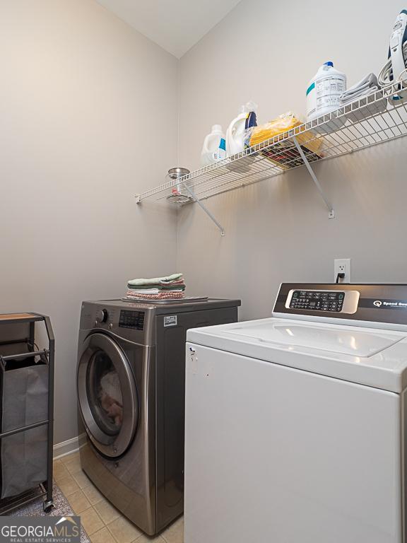 clothes washing area with light tile patterned flooring and washing machine and clothes dryer