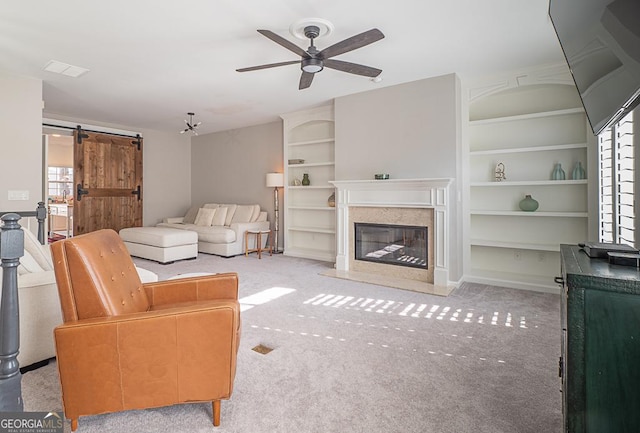 carpeted living room featuring ceiling fan, a barn door, and a fireplace