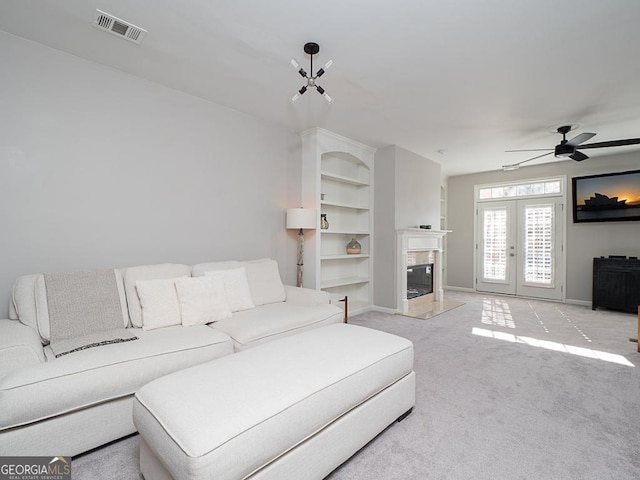 carpeted living room featuring ceiling fan, french doors, and a fireplace