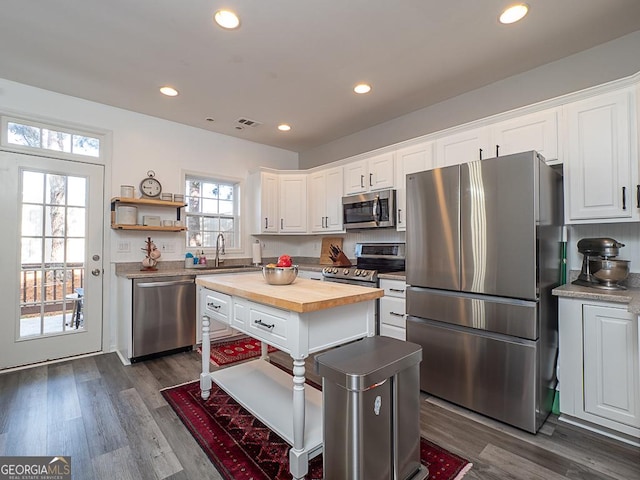 kitchen featuring a kitchen island, white cabinetry, wooden counters, and appliances with stainless steel finishes