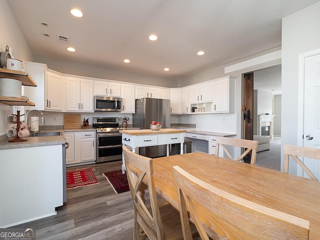 kitchen with a center island, dark hardwood / wood-style flooring, white cabinets, appliances with stainless steel finishes, and sink