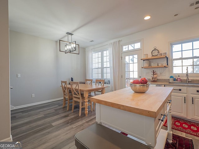 kitchen featuring a center island, a notable chandelier, sink, decorative light fixtures, and butcher block counters