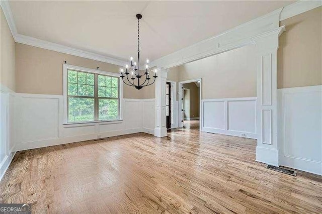 unfurnished dining area featuring a notable chandelier, crown molding, and hardwood / wood-style flooring