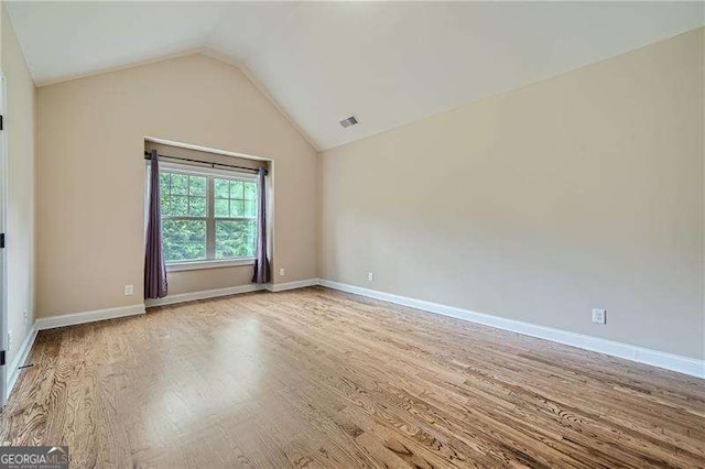 unfurnished room featuring light wood-type flooring and vaulted ceiling