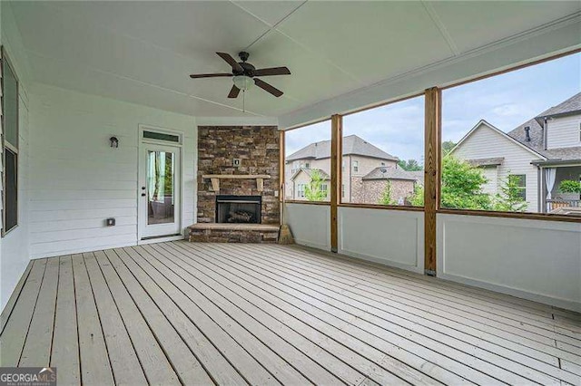 unfurnished sunroom featuring ceiling fan and a fireplace