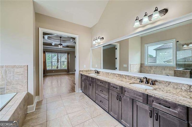 bathroom with a relaxing tiled tub, ceiling fan, tile patterned flooring, and vanity