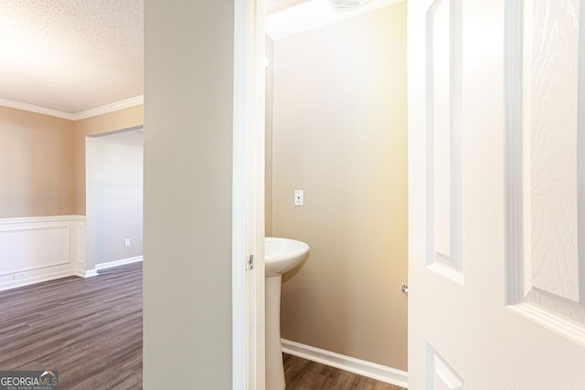 bathroom with a textured ceiling, crown molding, and hardwood / wood-style flooring