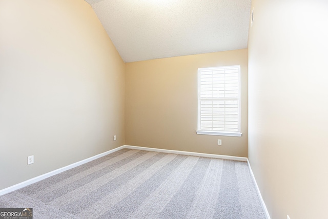 carpeted empty room featuring a textured ceiling and lofted ceiling