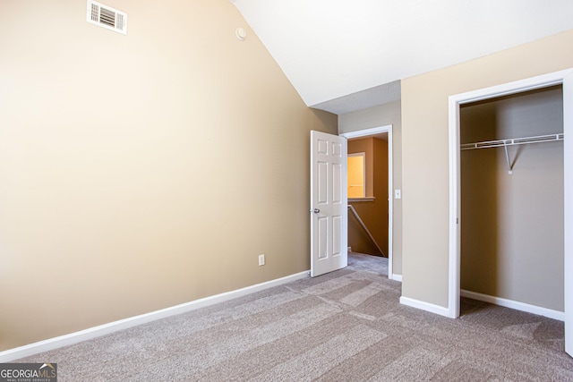 unfurnished bedroom featuring a closet, light carpet, and vaulted ceiling