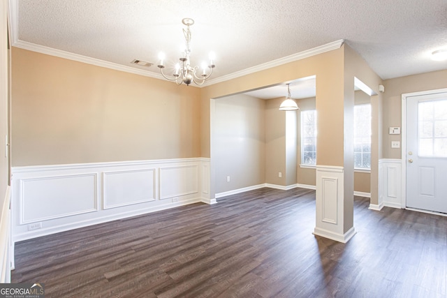 interior space with a textured ceiling, dark wood-type flooring, an inviting chandelier, and crown molding