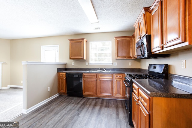 kitchen featuring black appliances, dark wood-type flooring, a textured ceiling, and sink