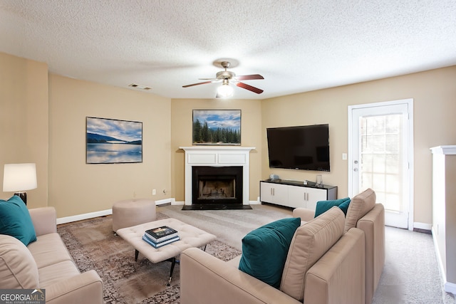 living room featuring carpet floors, ceiling fan, and a textured ceiling