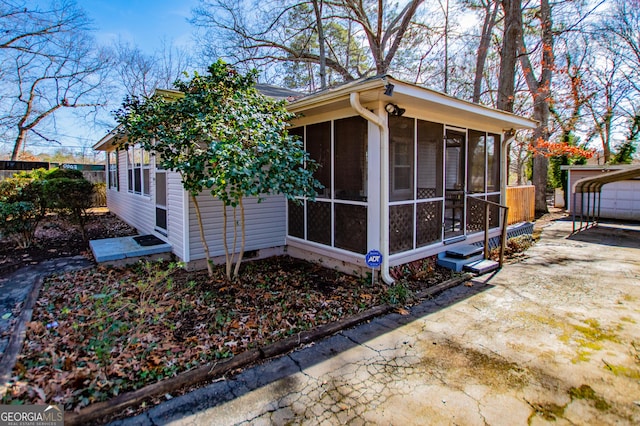 view of side of property featuring a sunroom and a carport