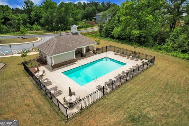 pool with fence, an outdoor structure, an exterior structure, a patio, and a yard