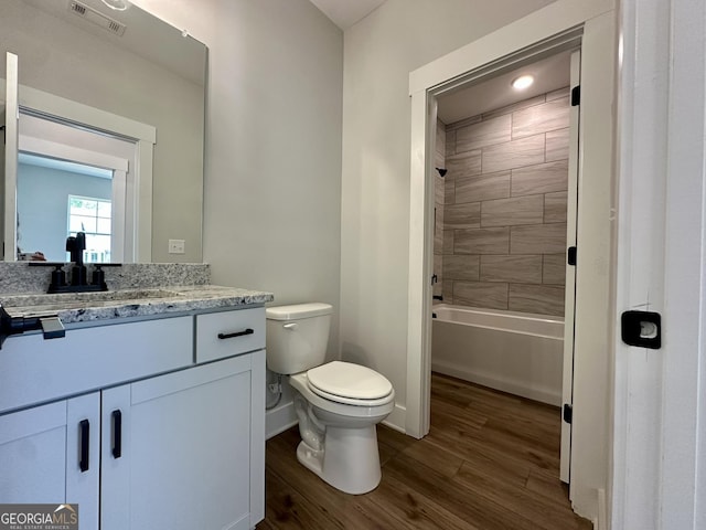 bathroom featuring visible vents, wood finished floors, baseboards, vanity, and toilet