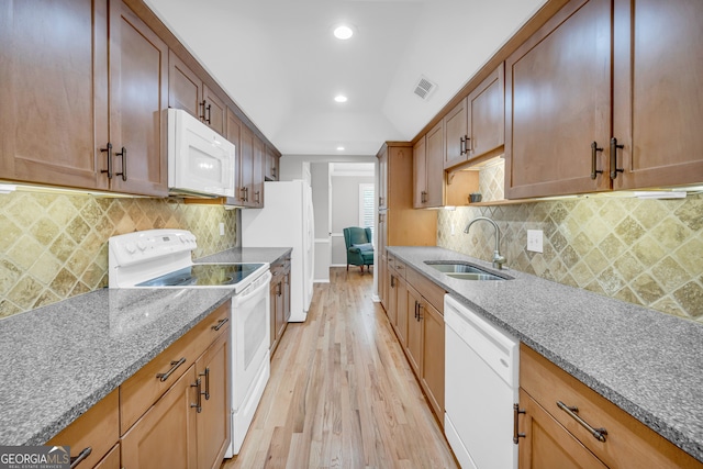 kitchen with white appliances, light wood-type flooring, light stone counters, sink, and tasteful backsplash