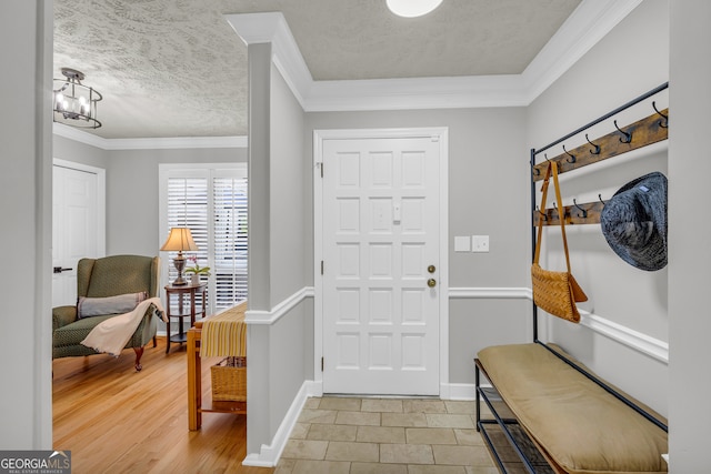 entrance foyer with a textured ceiling, a notable chandelier, light hardwood / wood-style floors, and crown molding