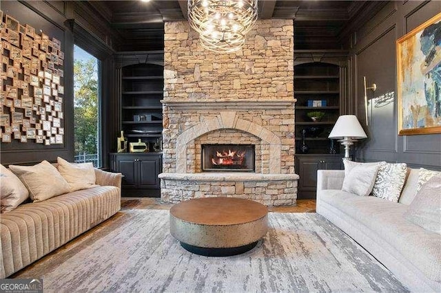 living room with a fireplace, an inviting chandelier, built in features, and hardwood / wood-style flooring