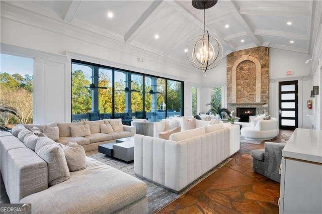 living room with a stone fireplace, parquet flooring, a chandelier, a towering ceiling, and beamed ceiling