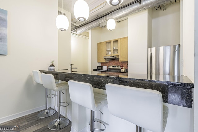 kitchen with decorative light fixtures, backsplash, dark hardwood / wood-style flooring, a kitchen bar, and stainless steel appliances