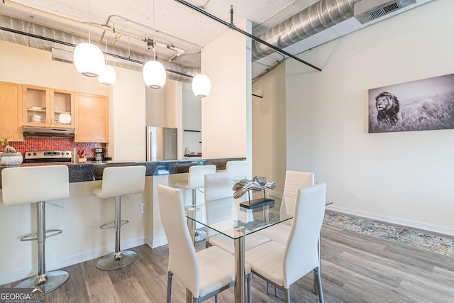 dining area featuring a towering ceiling and light hardwood / wood-style floors