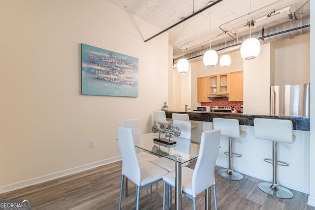 dining space with a towering ceiling and dark wood-type flooring