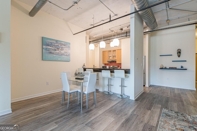 dining area featuring a towering ceiling and hardwood / wood-style floors