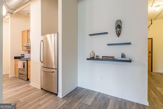 kitchen featuring a towering ceiling, light hardwood / wood-style flooring, and appliances with stainless steel finishes