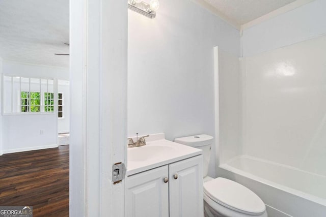 full bathroom with a textured ceiling, hardwood / wood-style flooring, toilet,  shower combination, and vanity