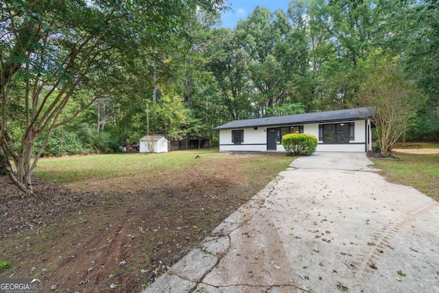 ranch-style home featuring a front yard and a shed