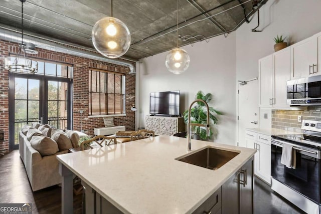 kitchen with stainless steel appliances, brick wall, white cabinets, decorative light fixtures, and sink