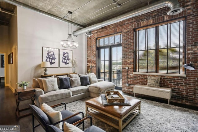 living room with brick wall, an inviting chandelier, and french doors