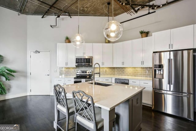 kitchen featuring appliances with stainless steel finishes, pendant lighting, white cabinetry, and sink