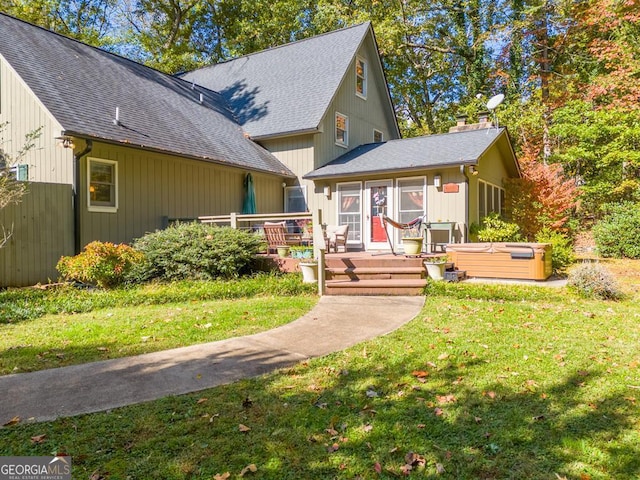 view of front facade featuring a front yard, a hot tub, and a wooden deck