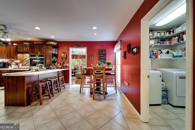 dining area with ceiling fan, light tile patterned flooring, and washing machine and clothes dryer