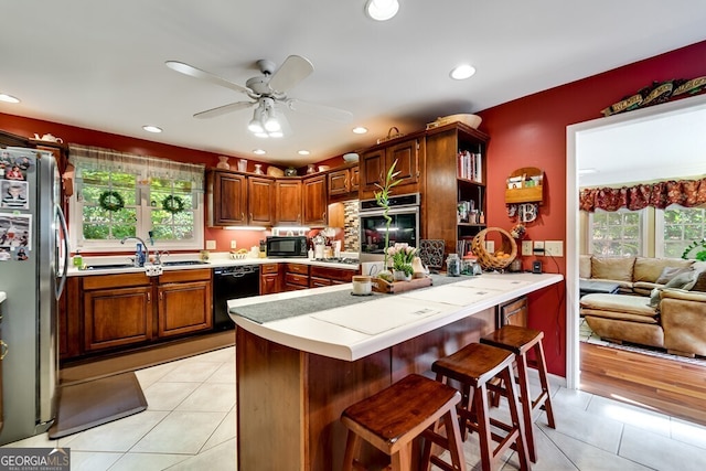 kitchen featuring black appliances, sink, kitchen peninsula, and light tile patterned floors