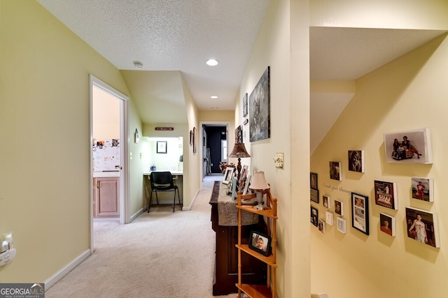 hallway featuring a textured ceiling and light colored carpet